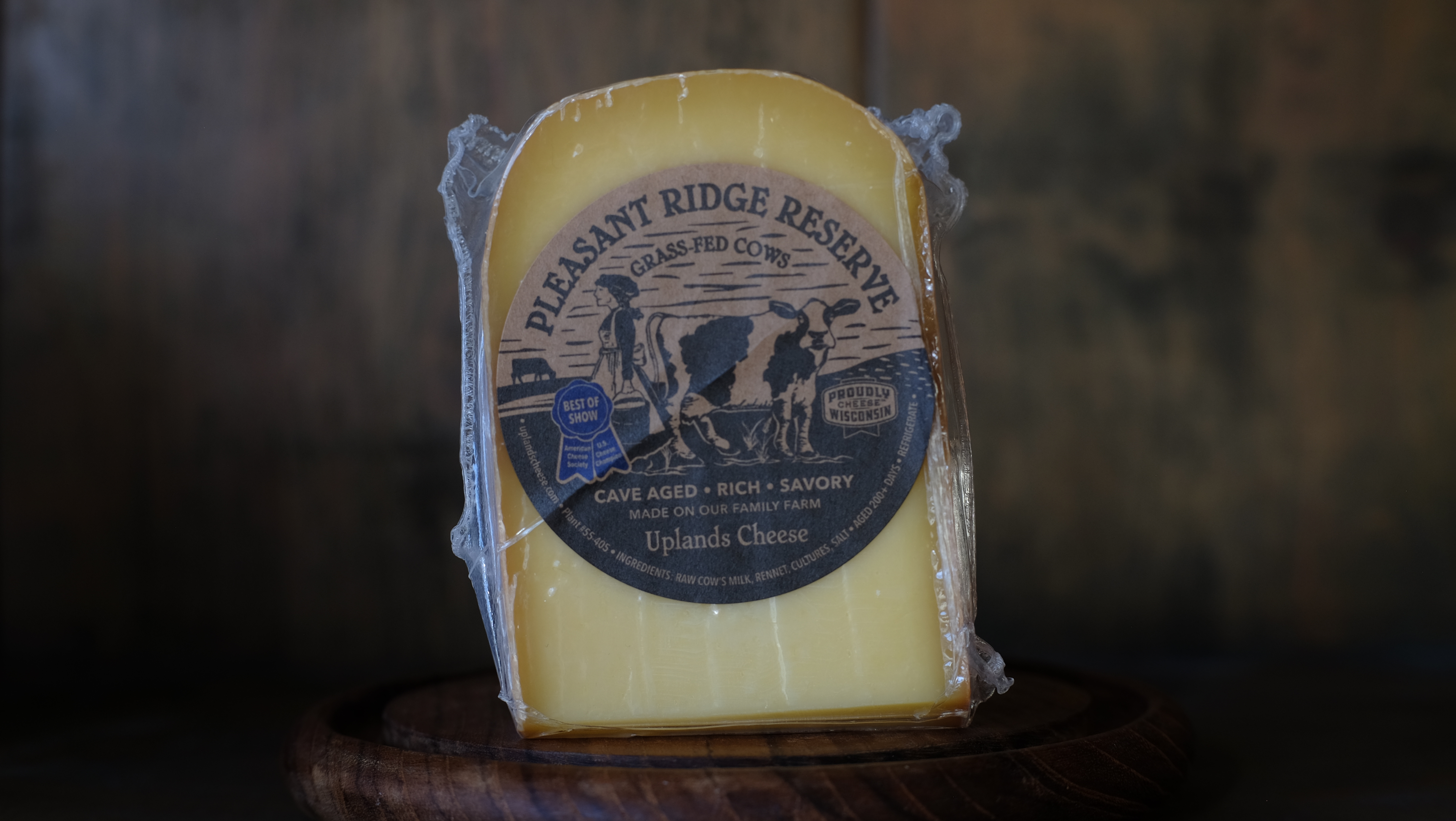 Wedge of Pleasant Ridge Reserve Alpine cheese on a wooden surface